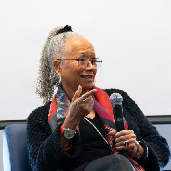 Ann Smith holds a microphone while seated in a chair